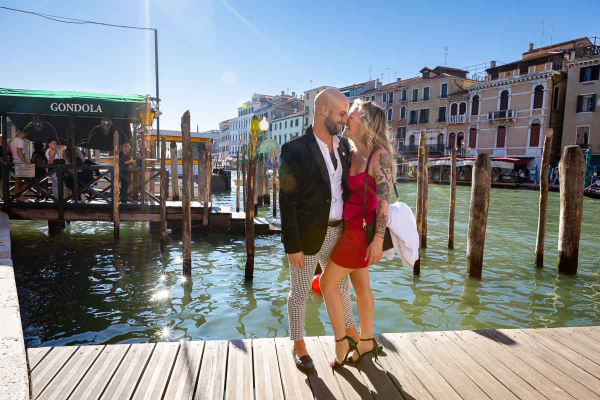 Taking engagement pictures together while standing on the gondola docks with canal grande in the backdrop in nice golden light 
