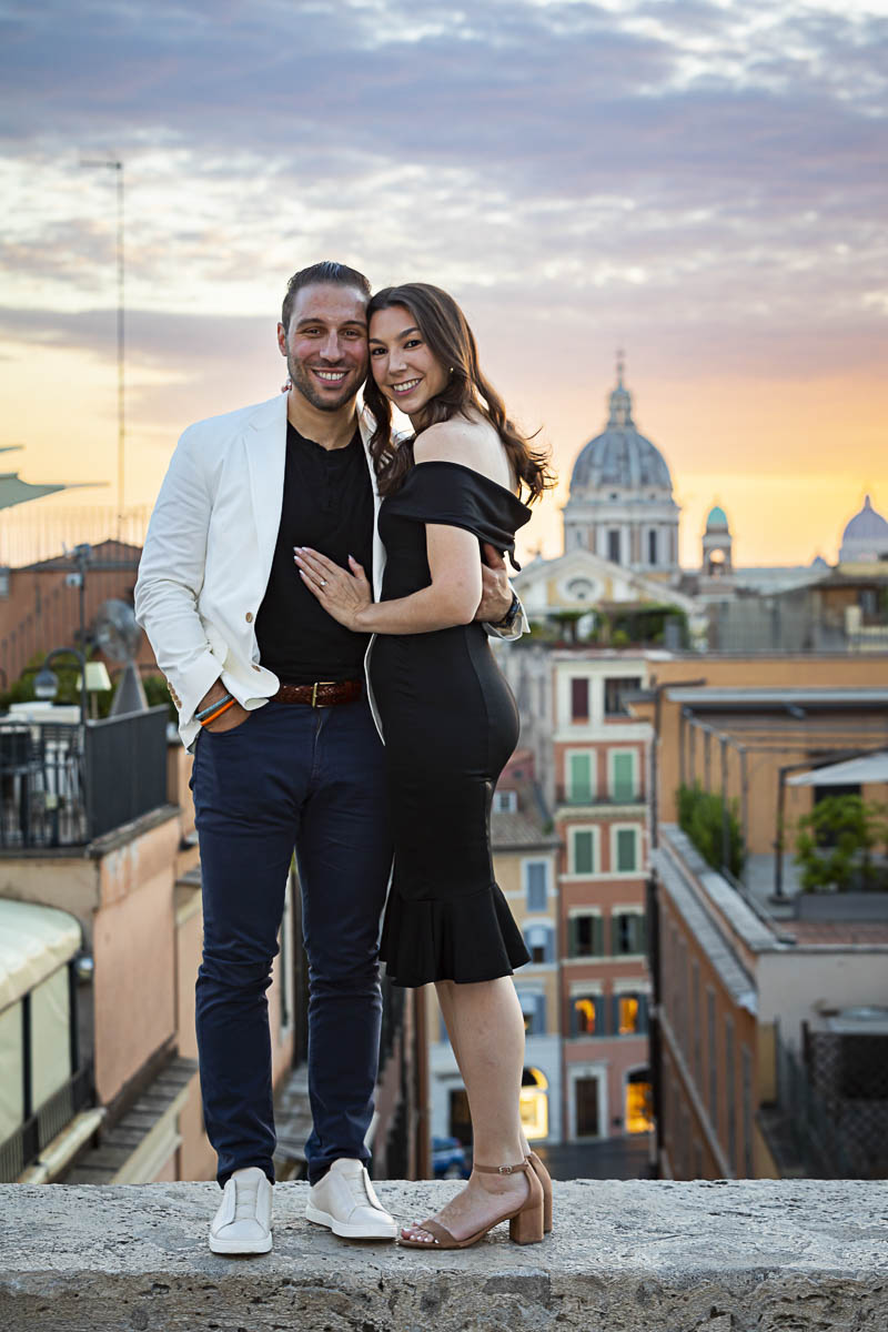Standing on a small wall with the stunning view of the city of Rome in the background at sunset
