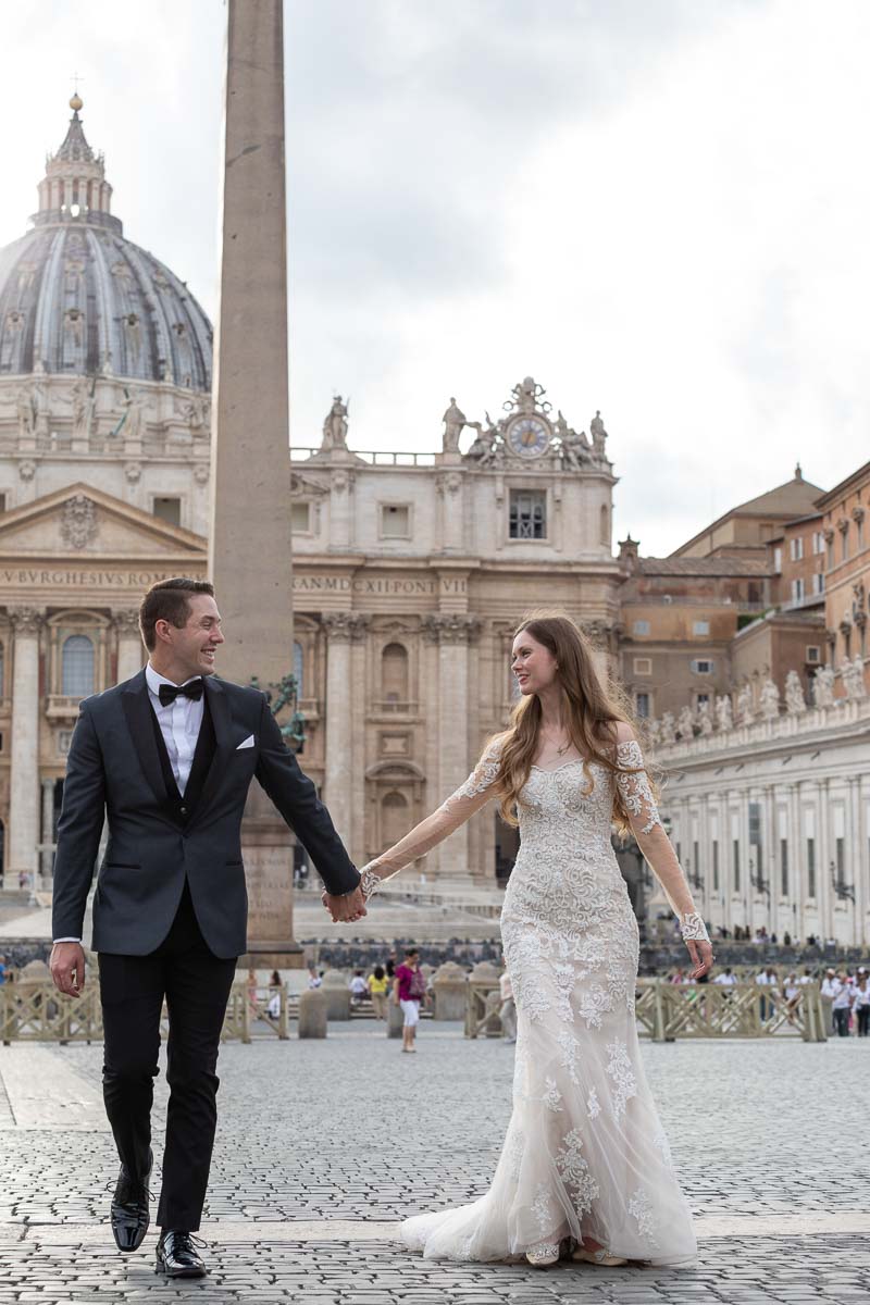 Walking together in wedding attire in St. Peter's square in Rome Italy