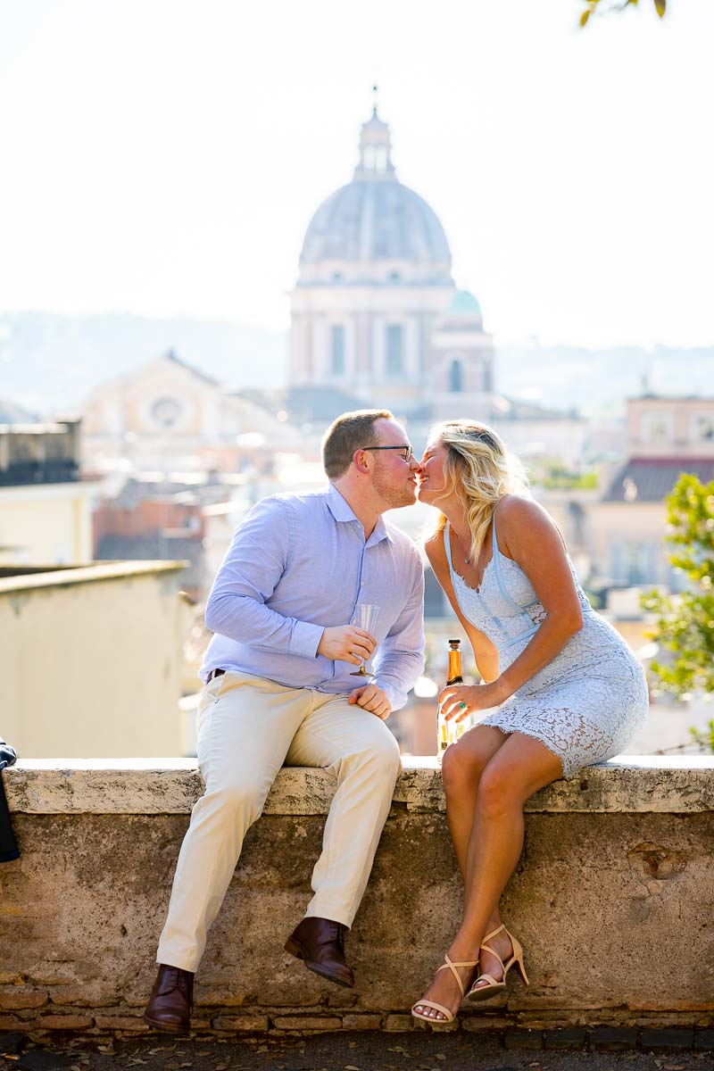 Couple kissing before the roman skyline view while toasting with Italian sparkling wine 