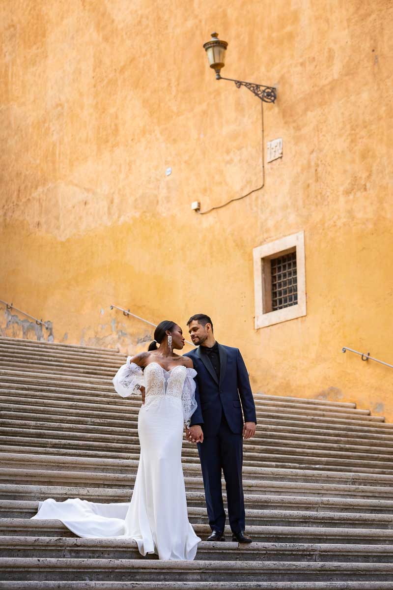 Standing on a large marble staircase taking unique and creative wedding photos. Image take in Rome's Piazza del Campidoglio