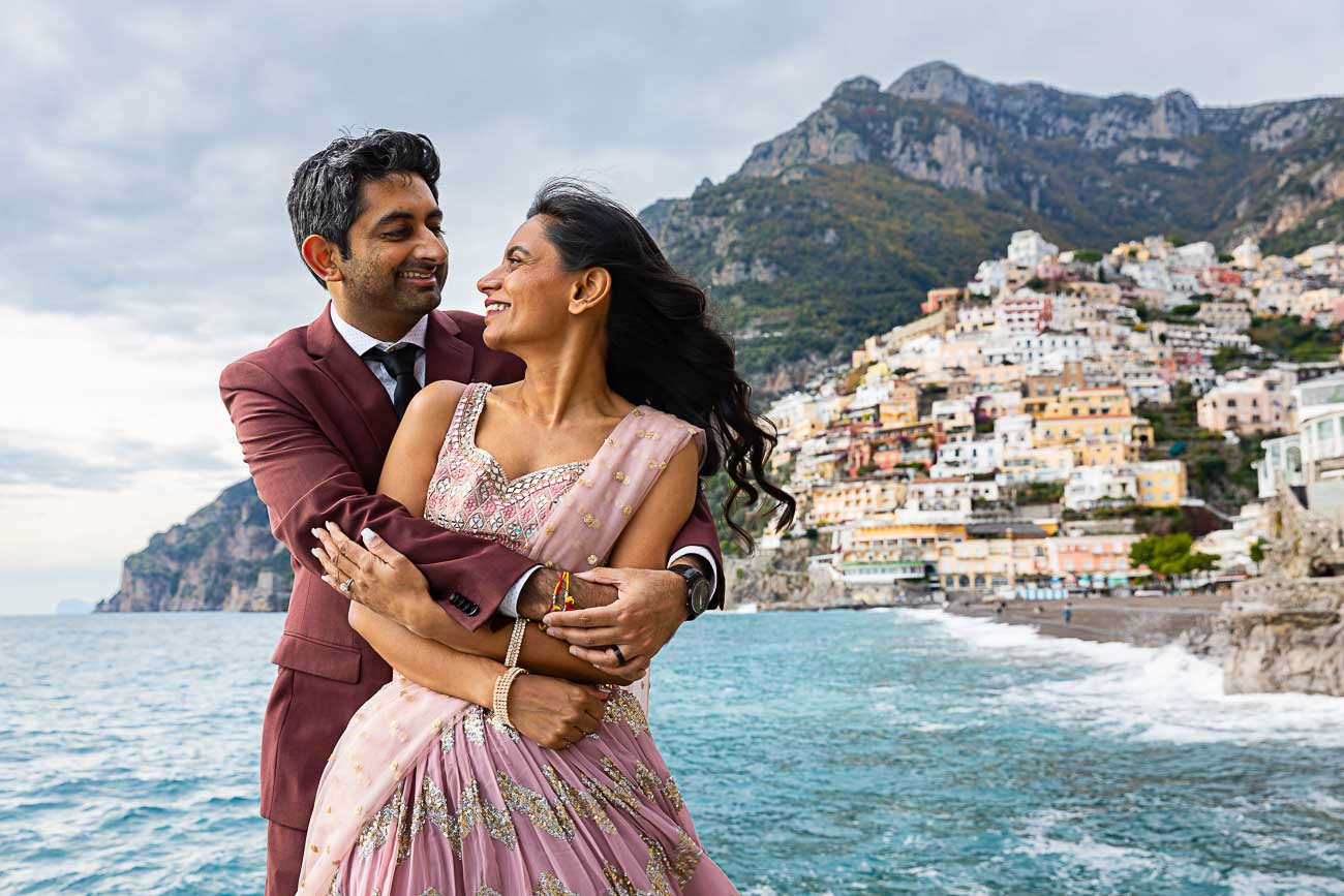 Couples Photo in Amalfi and Positano. Bust up portrait picture. Posed on the beach with the town in the far distance