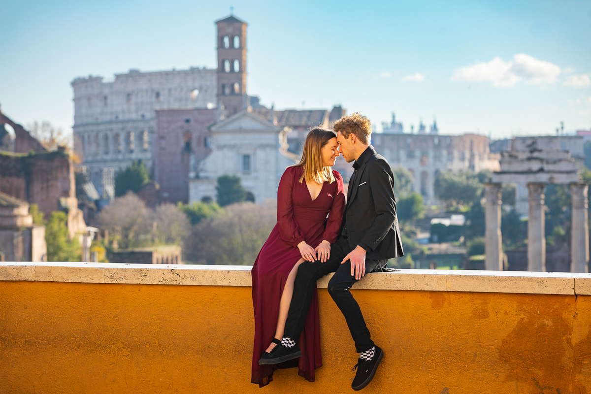 Sitting down on a ledge before the distant view of the Roman Colosseum and ancient Rome 