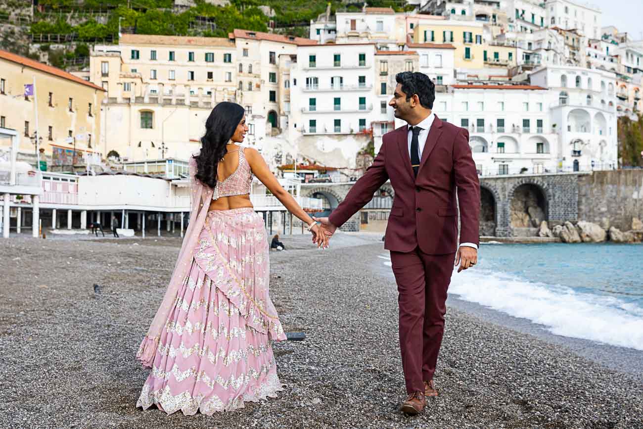 Walking on the beach of Amalfi reaching out hands to one another 