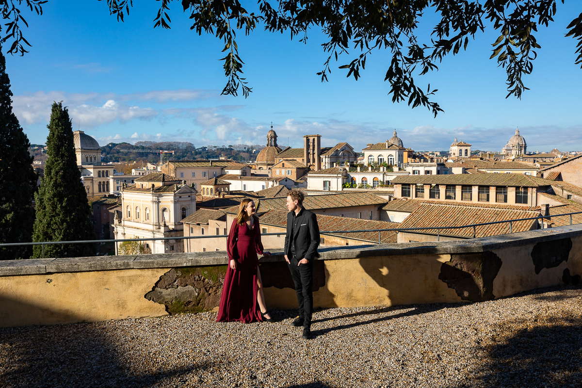 Wide angle view picture of a couple standing before the sweeping view of the ancient city of Rome 