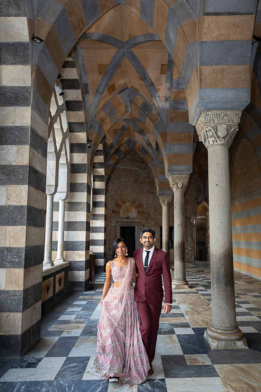 Walking images of a couple in between the columns of the church of Amalfi in Italy