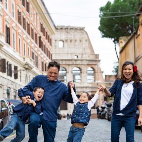 Fun family picture taken in Rome Italy while walking on a cobblestone alleyway leading to the Roman Colosseum in the far distance
