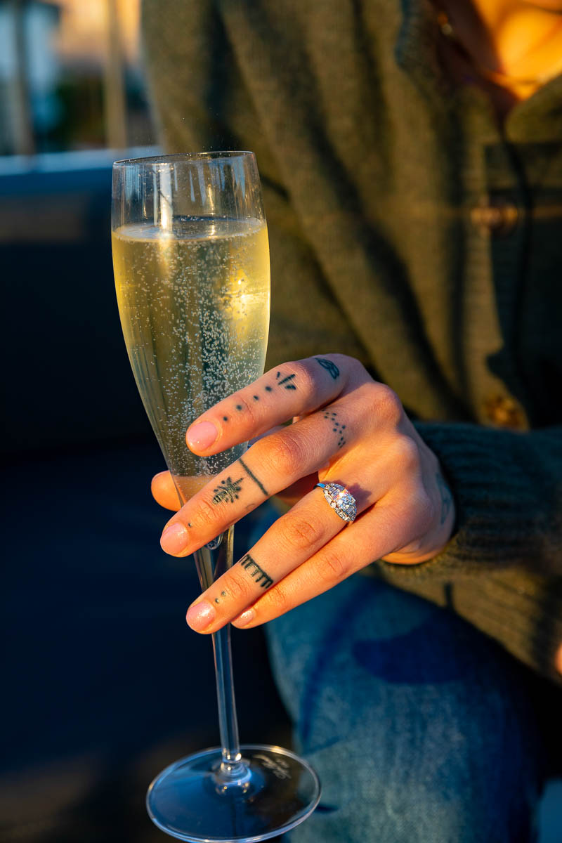 Close up of the engagement ring while holding a glass flute containing prosecco sparkling wine