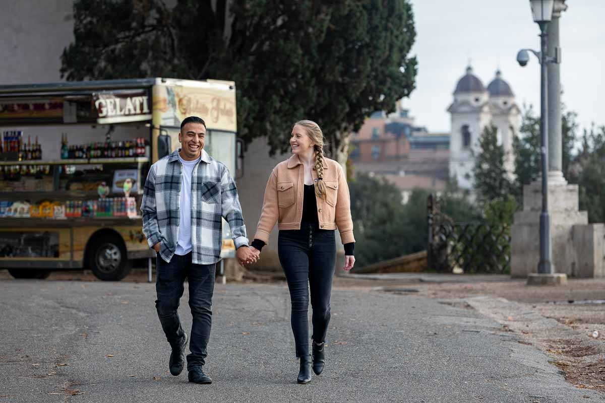 Walking together holding hands with church trinità dei monti in the background