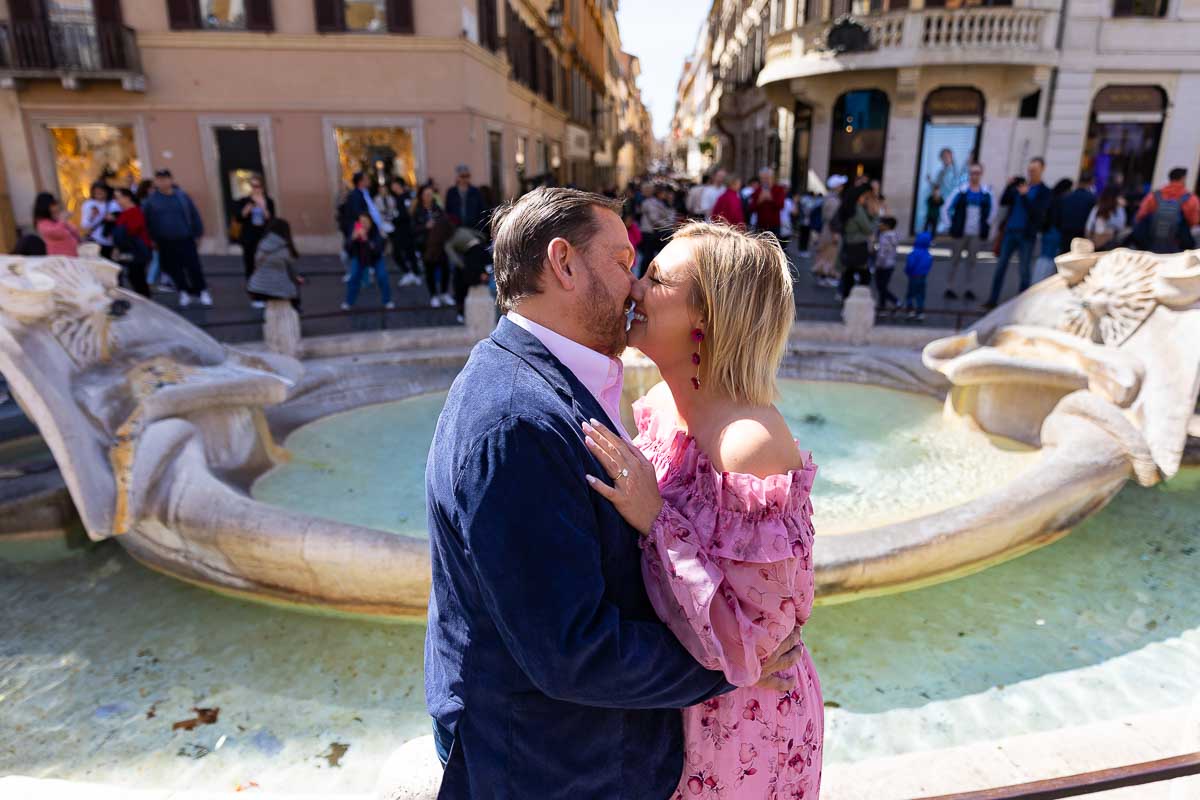 Couple kissing by the Barcaccia water fountain with the subject in focus and the background out of focus 