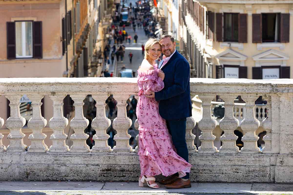 Portrait picture of a couple posing in front of the marble balconade found at the Spanish steps in Rome