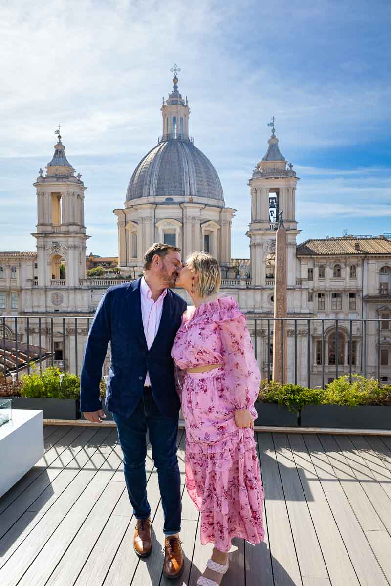 Walking and kissing together on a rooftop terrace with an incredible view of a church in Rome