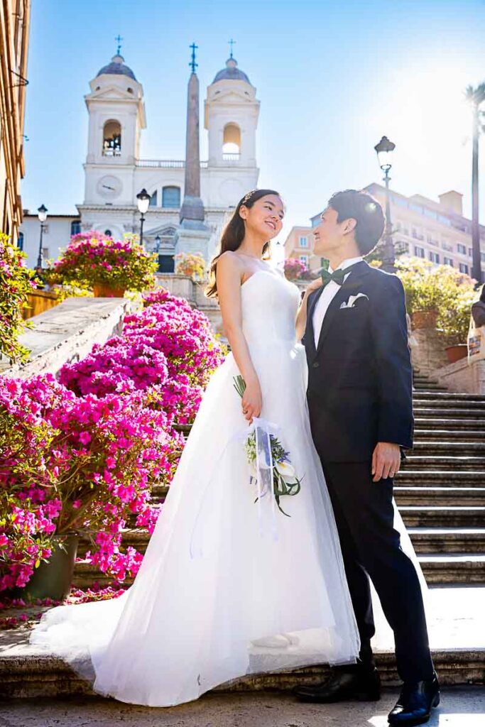 Bride and groom standing at the bottom of the Spanish steps with all the flowers while posing for a wedding photoshoot