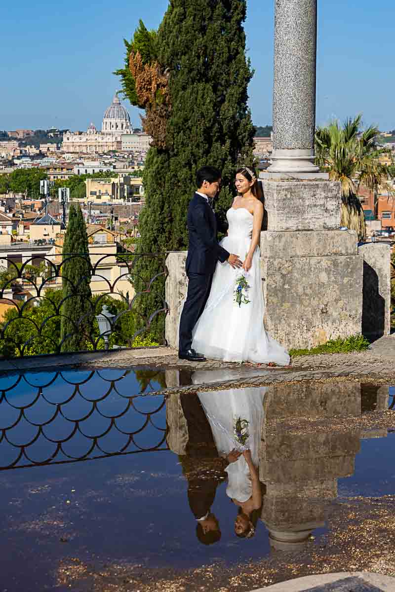 The water reflection of the groom and bride posed during a photo session at the Pincio park terrace 