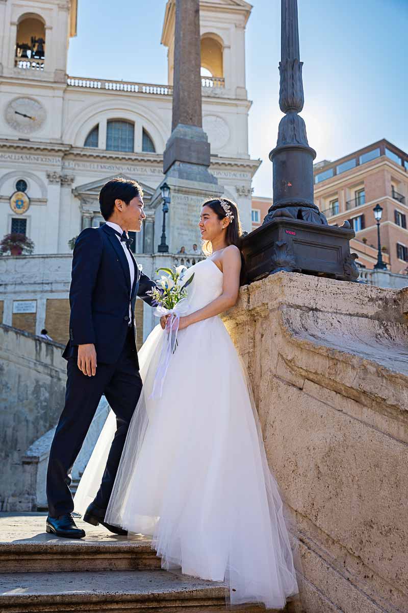 Couple posed on the Spanish steps with early morning light shining through the buildings 