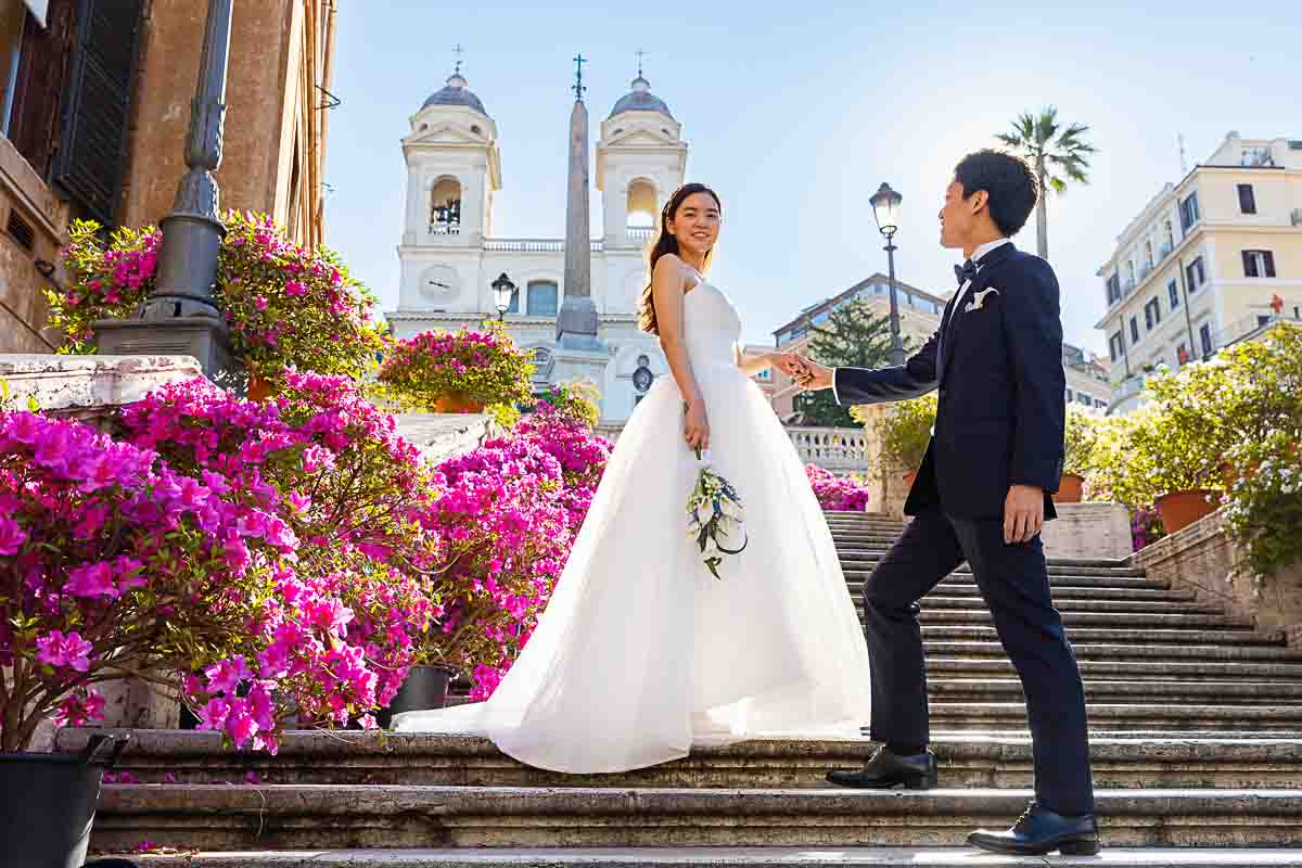 Wedding couple posing on the spanish steps surrounded by colorful flowers to celebrate spring in Rome 