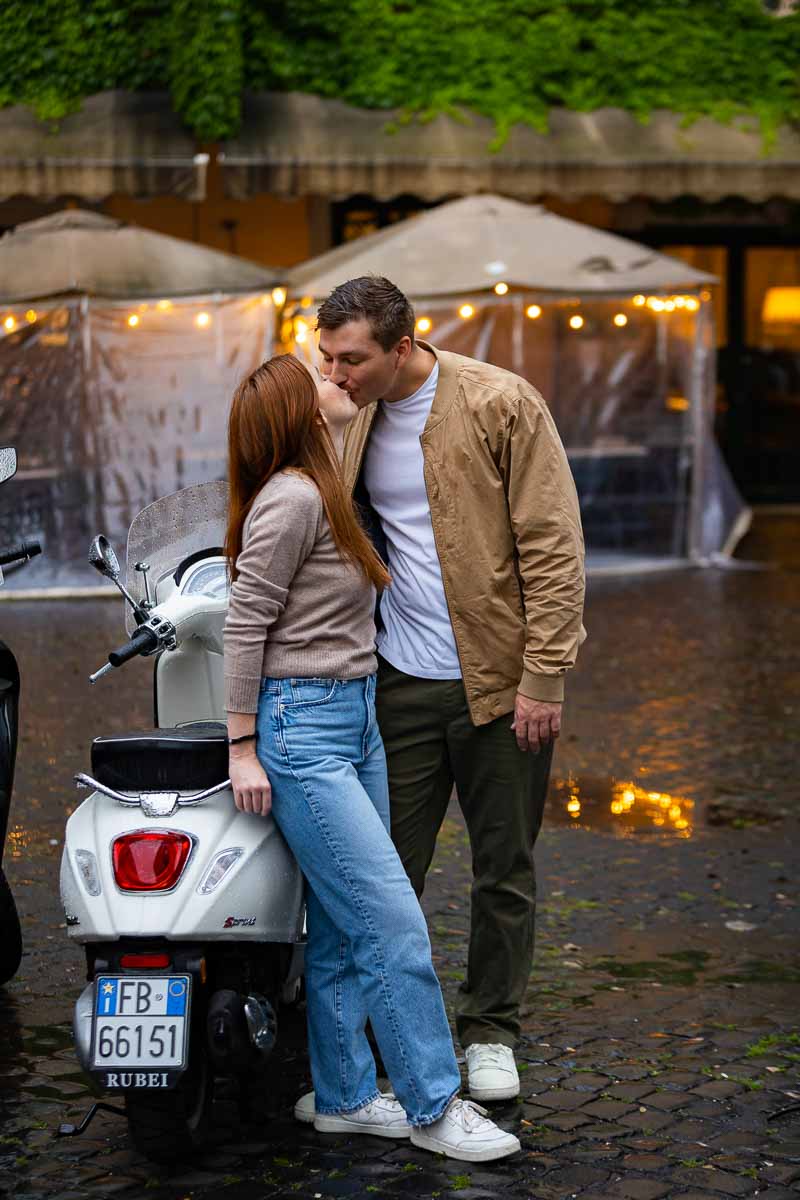 Couple taking engagement photos kissing a white scooter