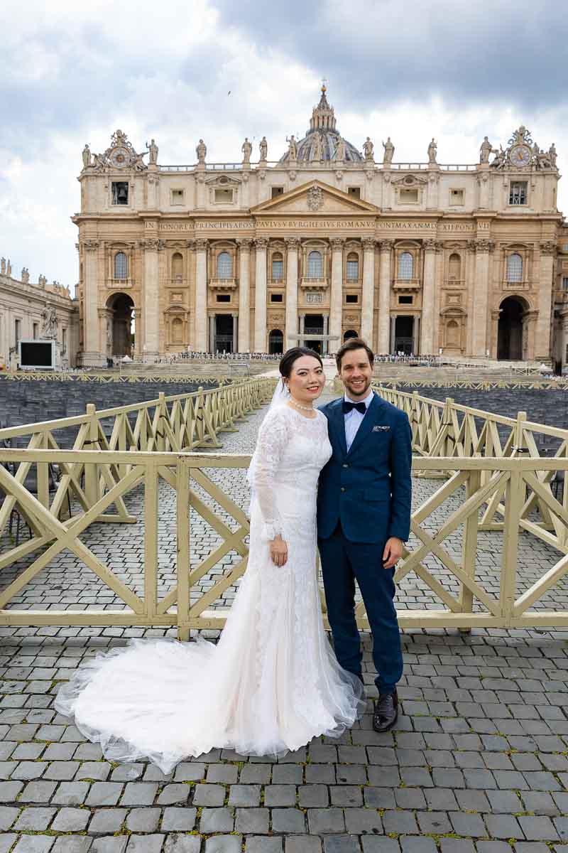 Bride and groom posing for a portrait picture taken underneath the basilica in Saint Peter's square in the Vatican. Rome, Italy