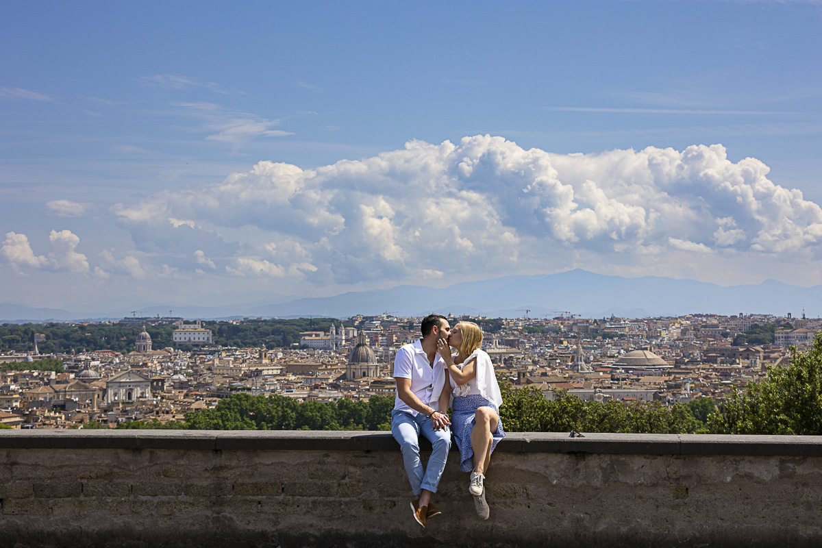 Couple portrait sitting down on the wall before the sweeping with of Rome during and engagement photoshoot