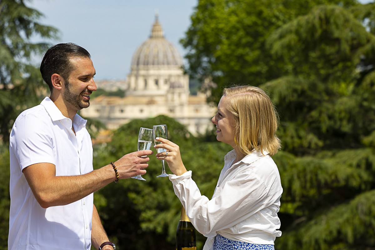 Toasting and celebrating engagement with a prosecco wine bottle with Saint Peter's dome in the far distance as background 