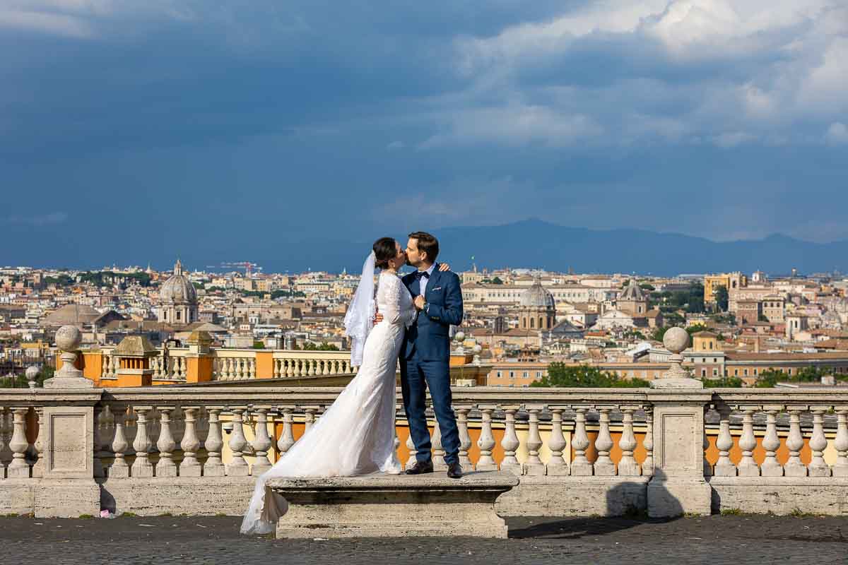 Standing on a marble bench with the Rome cityscape in the background during a wedding photography session in Rome 