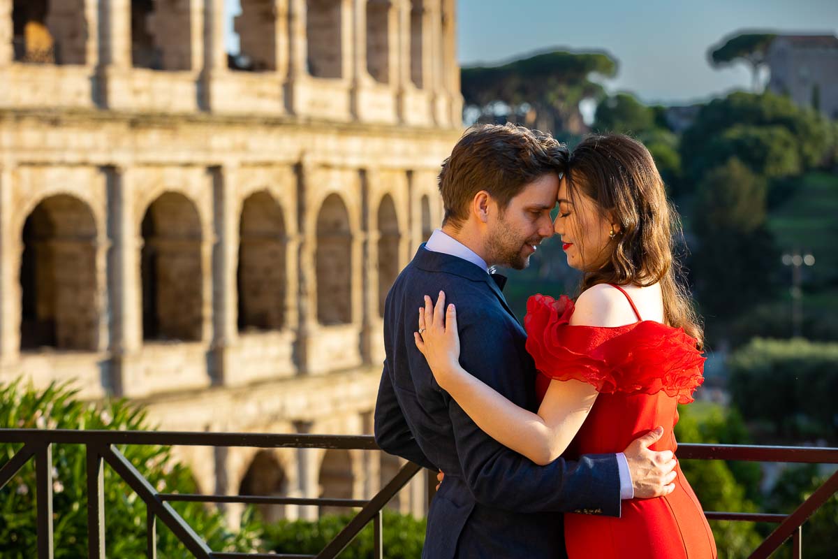 Romantic couple posing forehead to forehead in front of the Colosseum at dusk