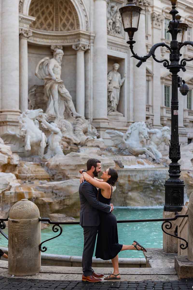 Standing sideways together by the Trevi fountain in the early morning light
