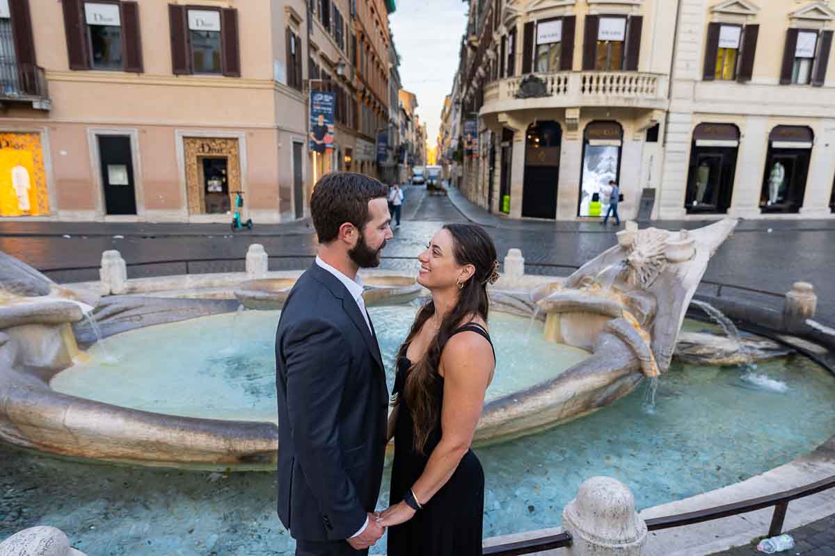 Couple portrait looking at each other at the bottom of Piazza di Spagna with pictures taken by the Barcaccia water fountain 