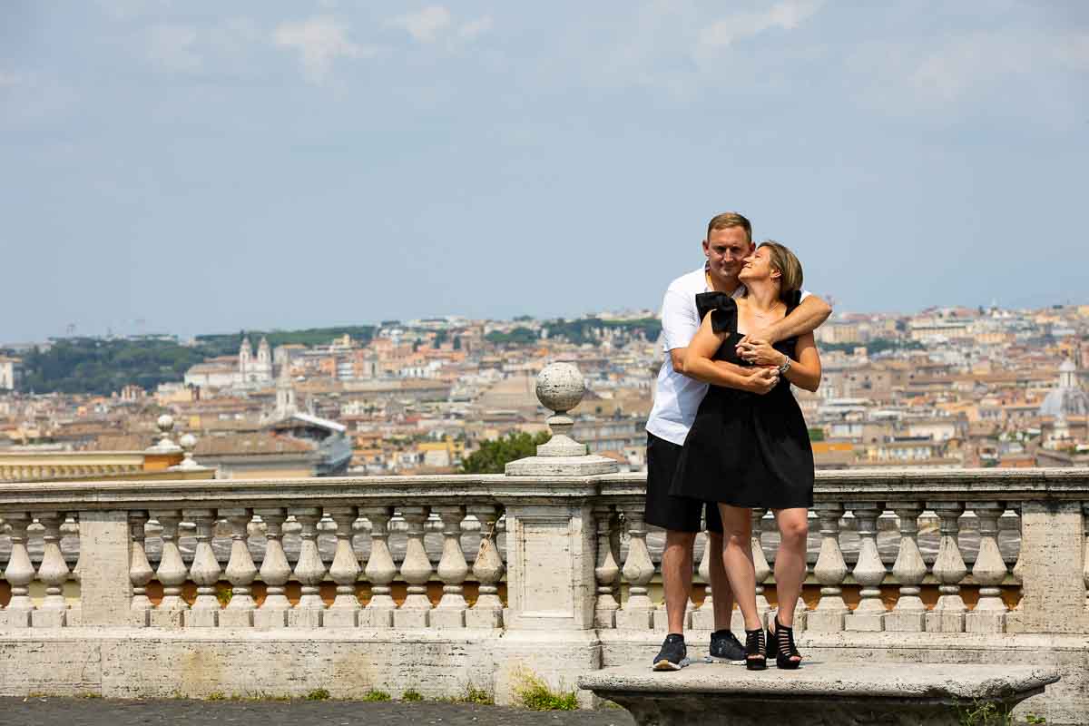 Portrait standing on a bench in front of the sweeping view of the roman skyline from the Janiculum hill. Rome Surprise Proposal Photography
