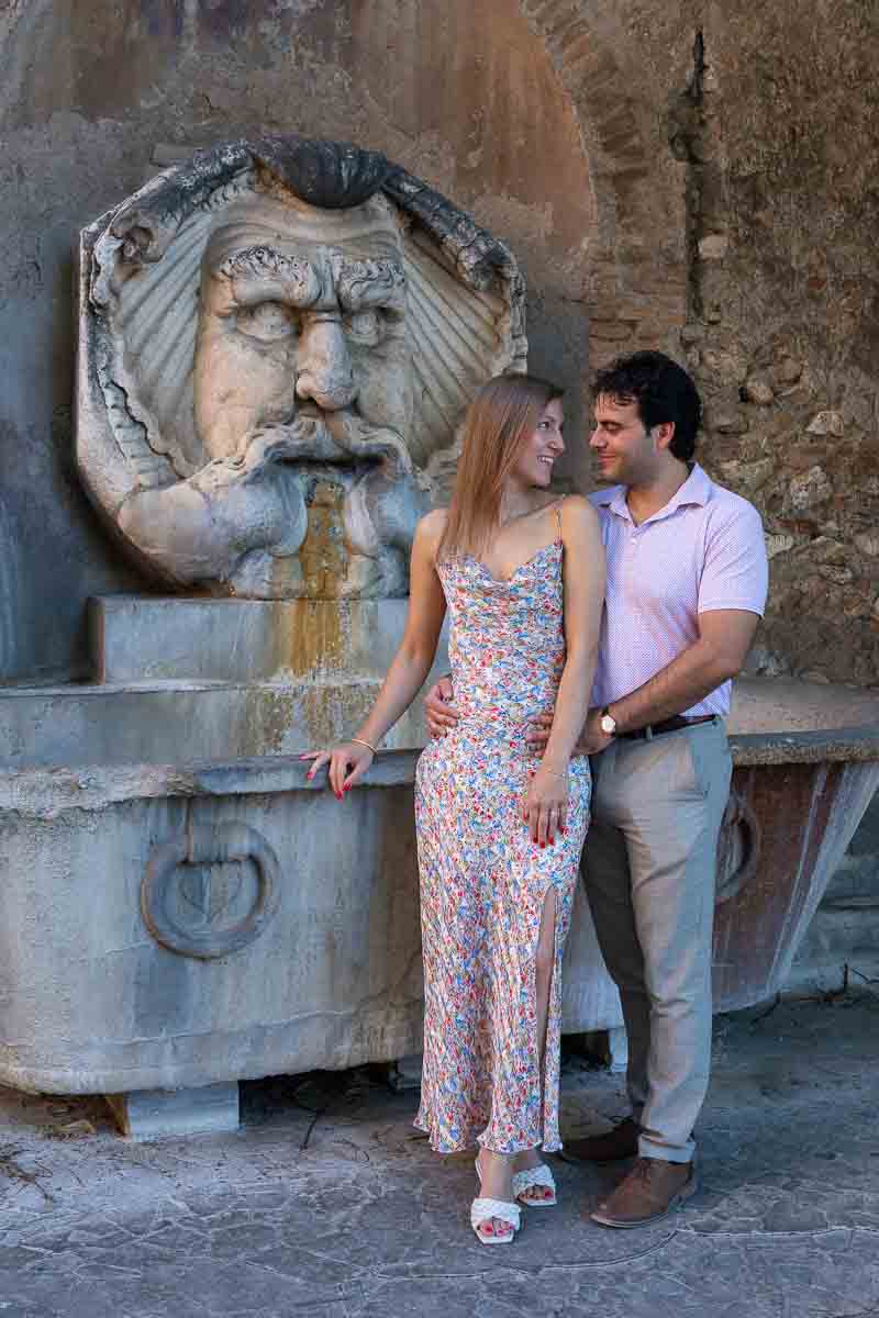 Couple portrait picture taken in color in front of a characteristic roman water fountain 