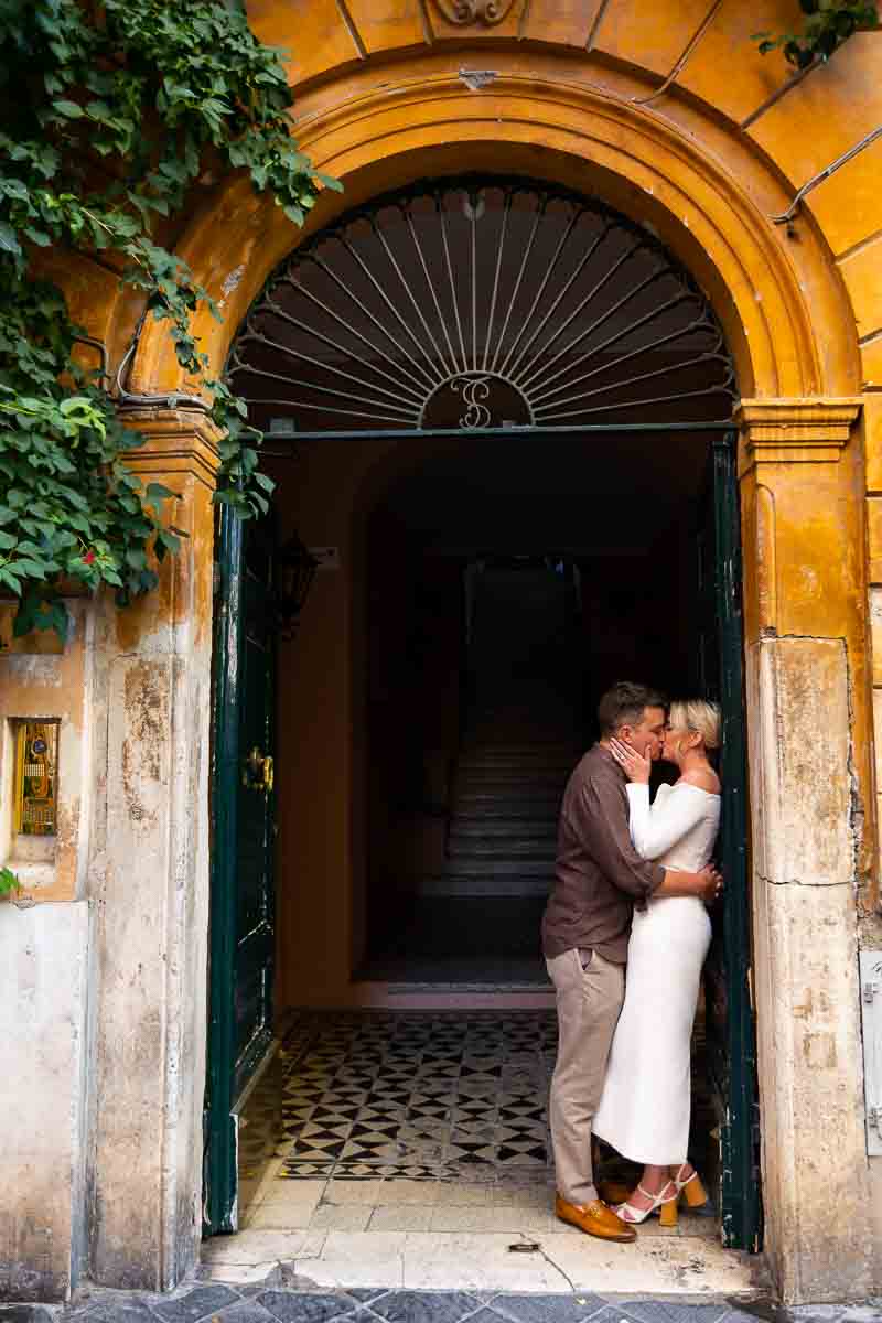 Kissing on the entrance of a roman doorway during engagement photos 