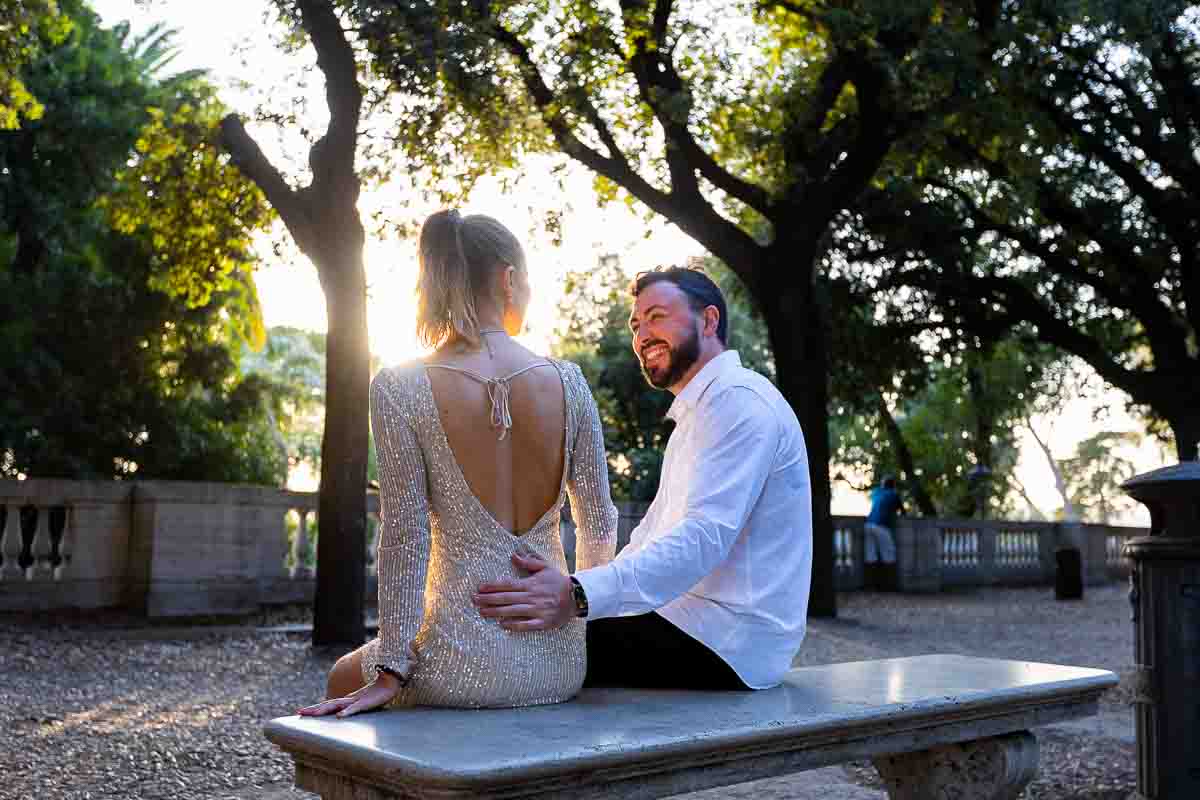 Couple in romance while sitting down on a marble bench during a couple photo shoot in Rome's Villa Borghese park