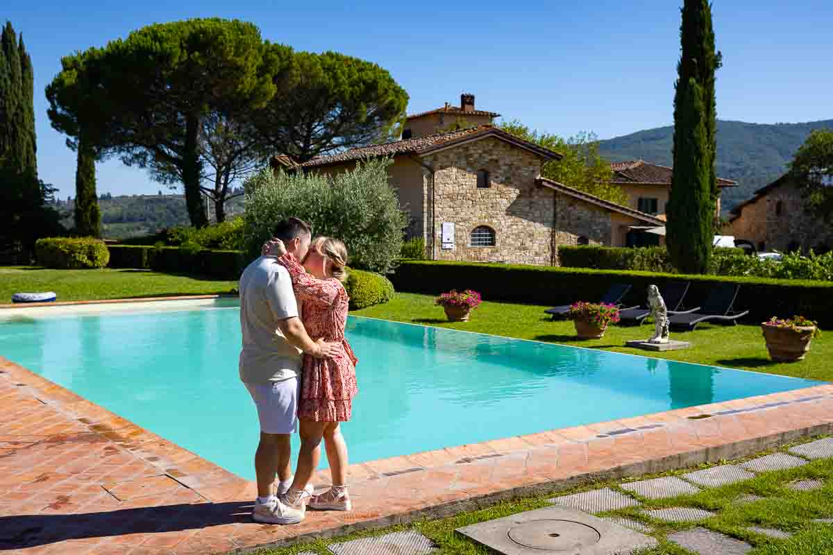 Couple engagement photos taken by the pool with the tuscany winery country house in the background 