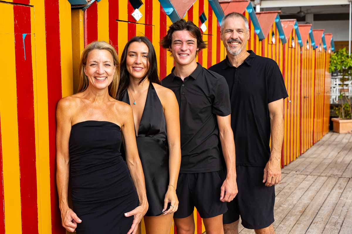 Family close up photographed next to red and yellow beach cabins 