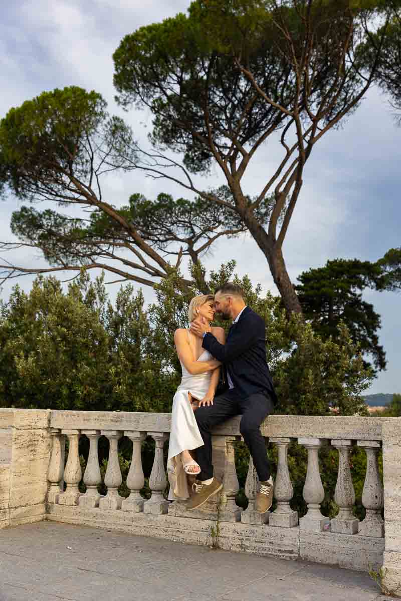 Sitting down by a marble railing during a rome photoshoot with Mediterranean pine trees in the background 