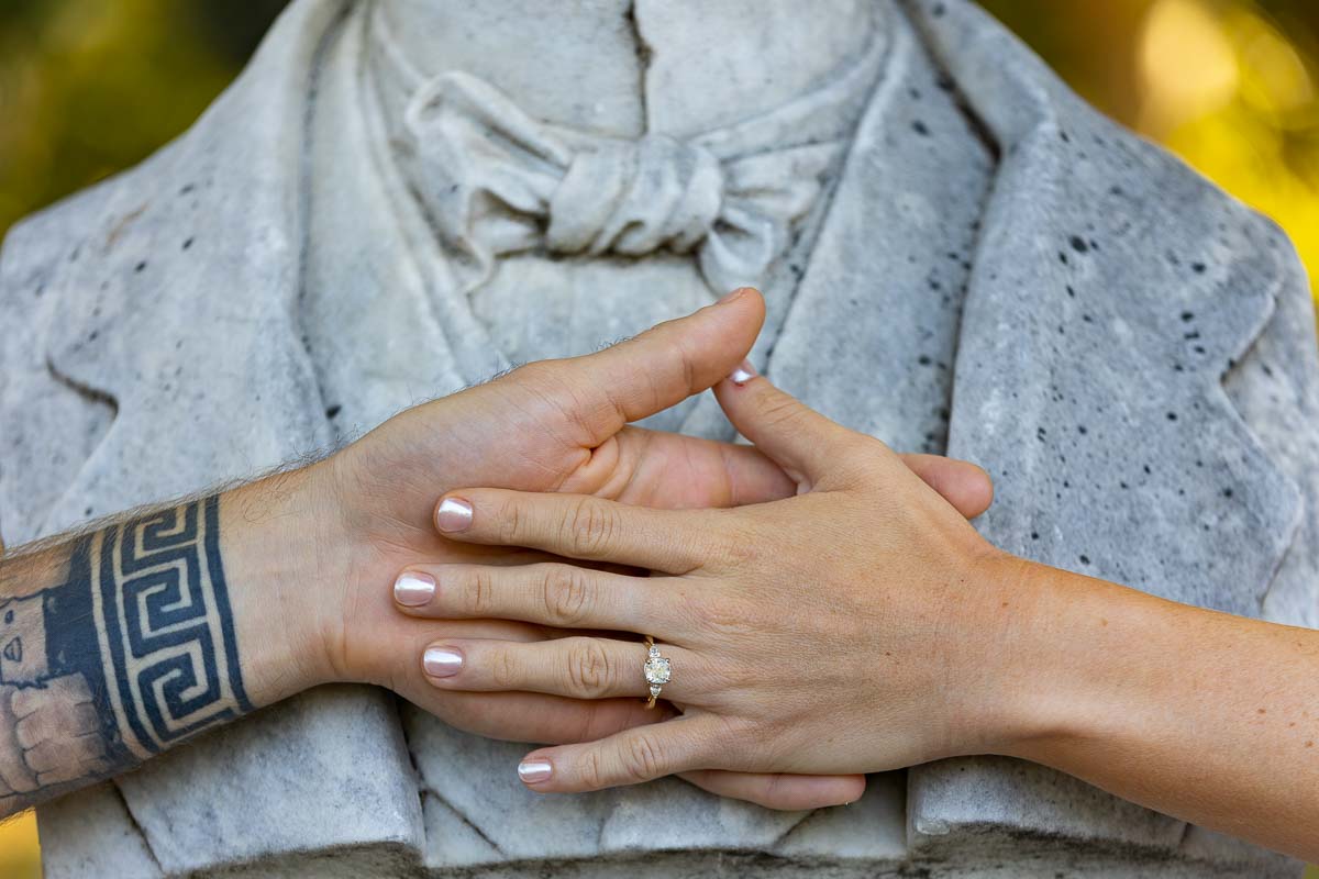 Close up image of the engagement ring photographed over a marble statue bust 