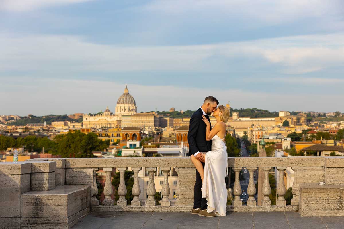 Beautiful morning picture of a wedding couple posing in front of the Rome skyline at the Pincio park terrace in Rome
