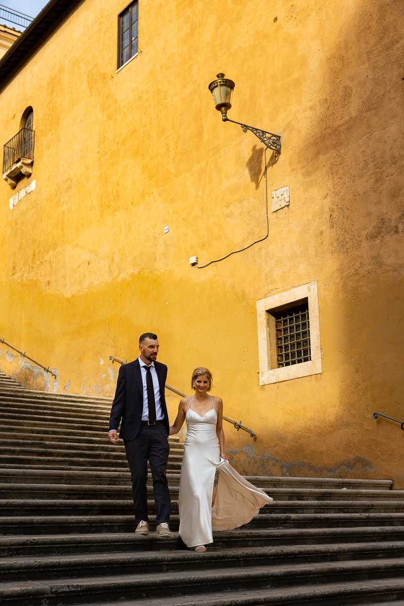 Groom and Bride walking hand in hand down the steps of Piazza del Campidoglio. Rome, Italy
