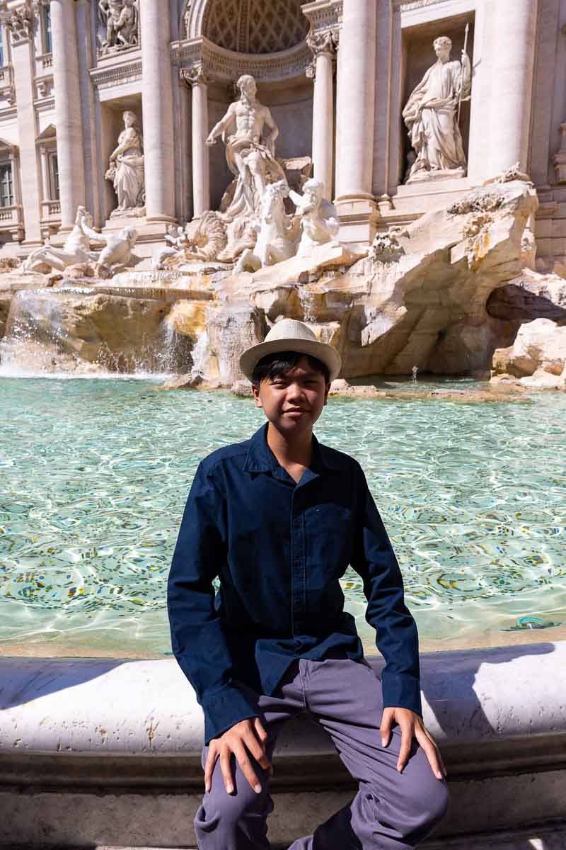 Son portrait shot at the Trevi fountain at the edge of the water 