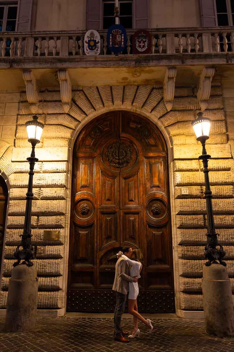 Photography portrait couple photoshoot in Rome by a wooden doorway lit at night by two light poles
