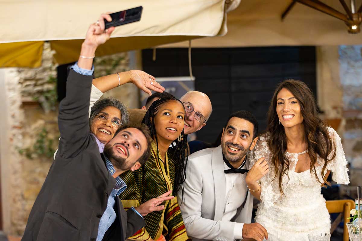 Selfie shot of the bride and groom together with friends and family