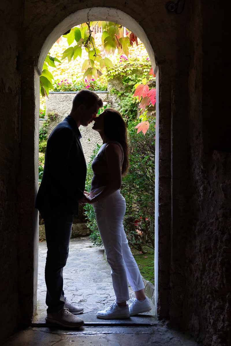 Silhouette image of a couple posing underneath an arch 