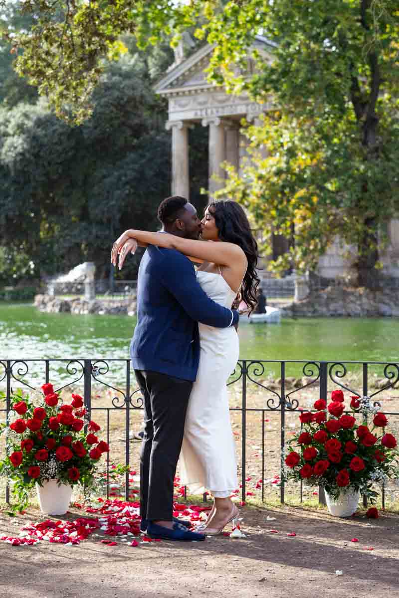 Couple proposal photoshoot with red roses in vases and red rose petals 