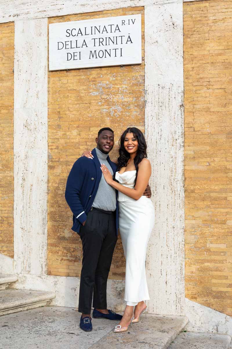 Taking pictures on the Spanish steps standing underneath the sign of Scalinata Trintà dei Monti 