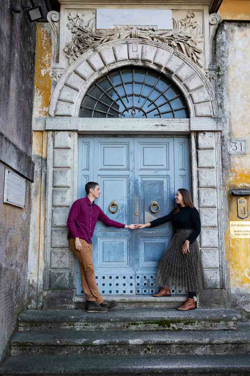In Love in Rome photo session of a couple taking pictures by an interesting doorway in Rome Italy. Taking engagement picture after a Janiculum hill proposal