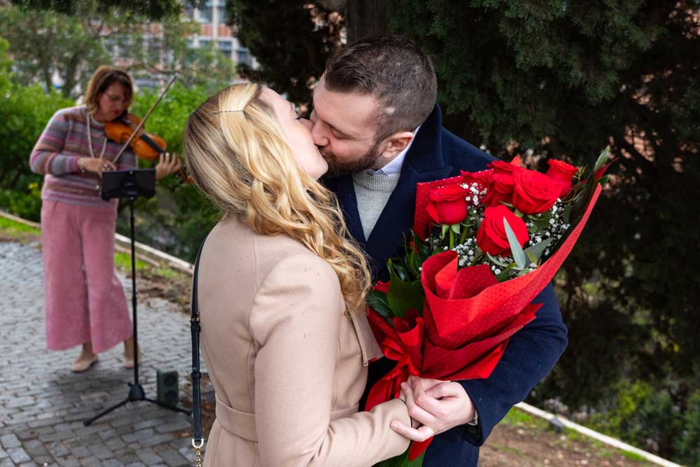 Couple kissing to the live sound of violin music during a wedding proposal in Rome 