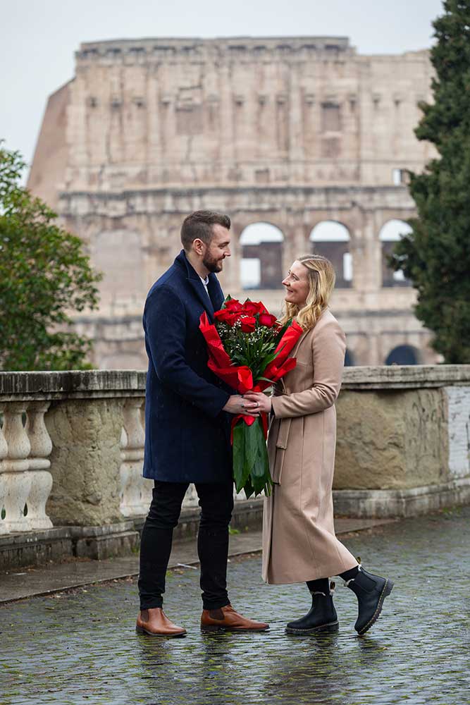 Standing together by the Colosseum with a bouquet of the red roses during a couple photoshoot. Colosseum view proposal 