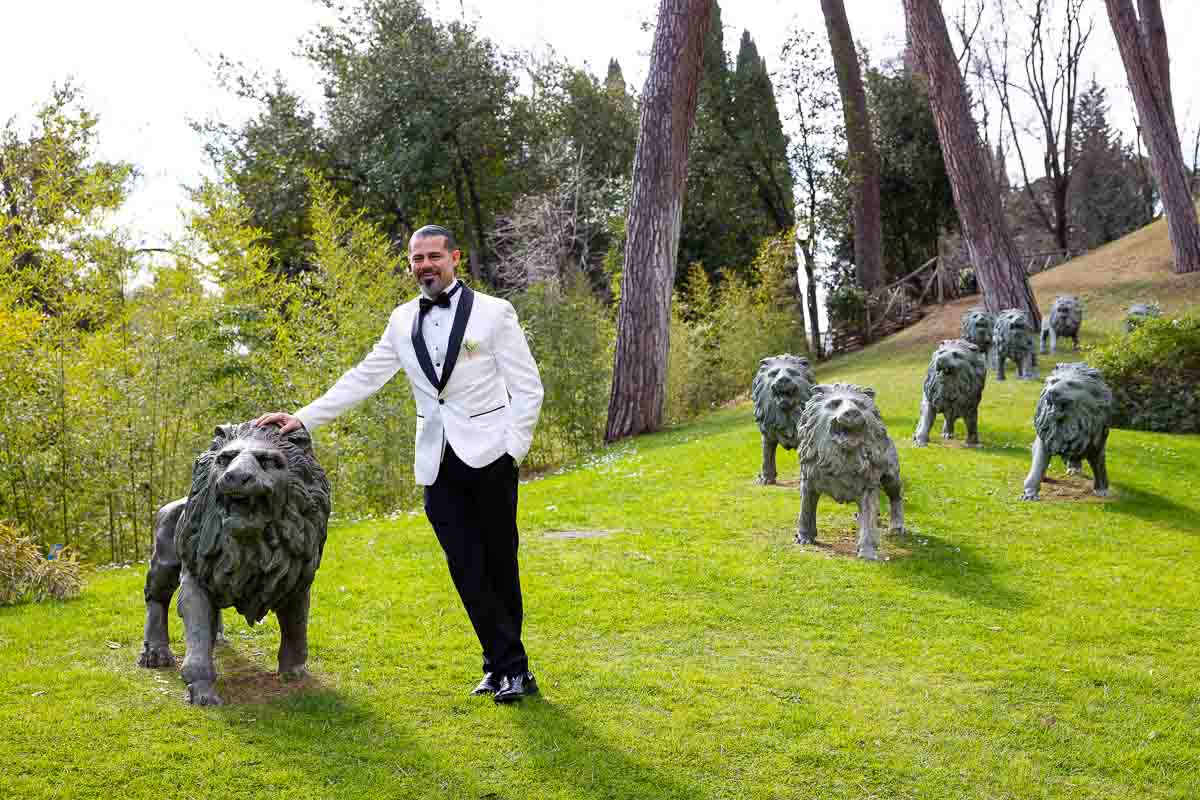 Groom solo shot standing by the statue of a lion found in the rear garden of the hotel 