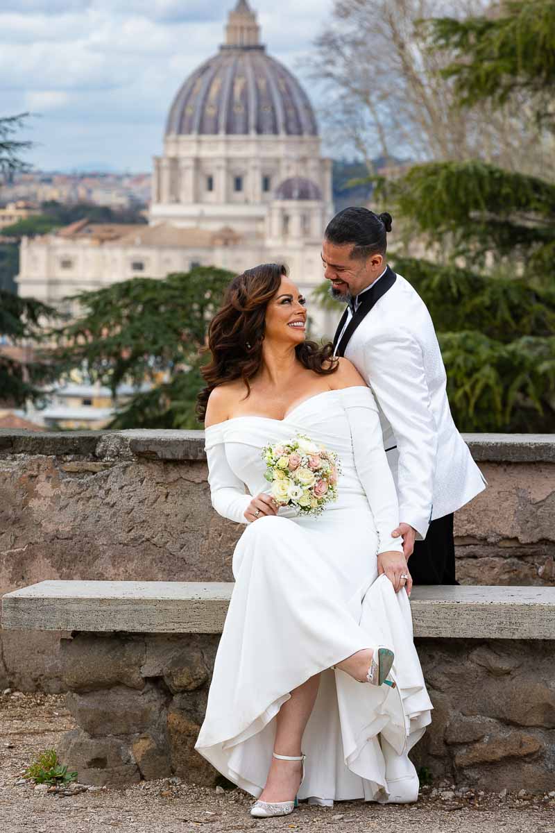 Groom and bride looking at each other before the stunning view of the Vatican church dome of Saint Peter's cathedral in the far distance