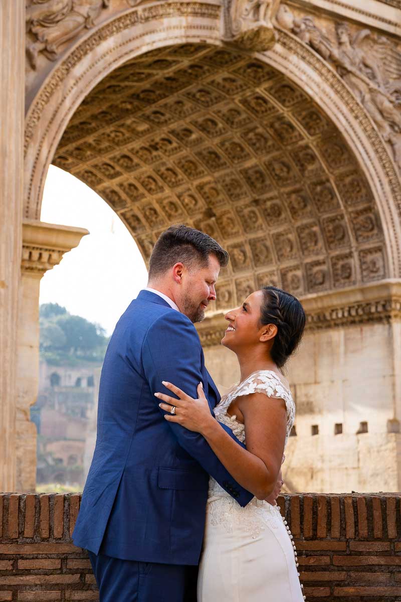 Standing together under the arch of Septimius Severus while taking elopement wedding pictures during a photoshoot in Rome Italy 